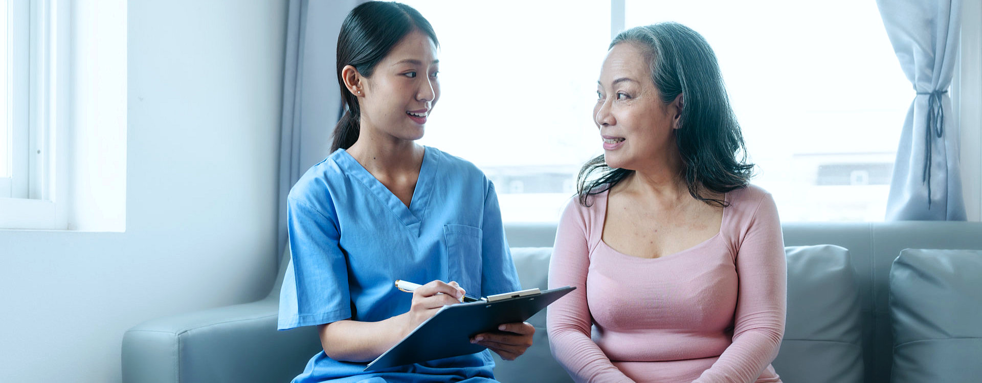 A nurse writing and talking to an elderly elderly woman