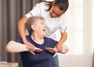 A nurse holding the arm of an elderly woman while an elderly man looking at them