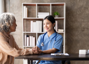 A nurse holding the hand of an elderly woman