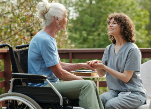 A nurse holding the arm of an elderly woman while an elderly man looking at them