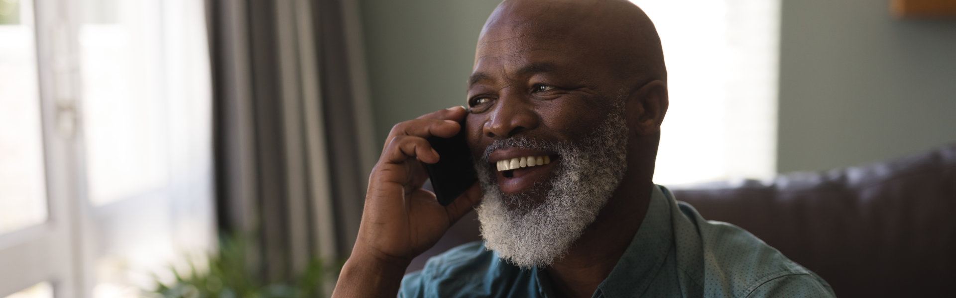 A elderly man laughing while holding a phone
