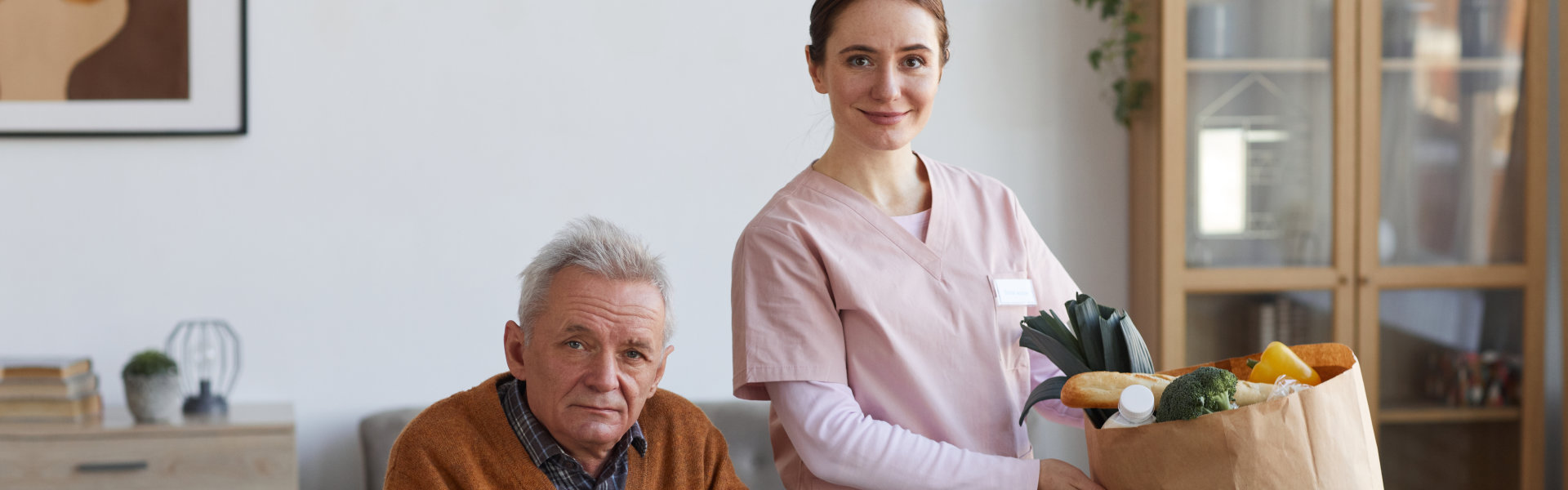 An elderly man and a nurse with grocery beside