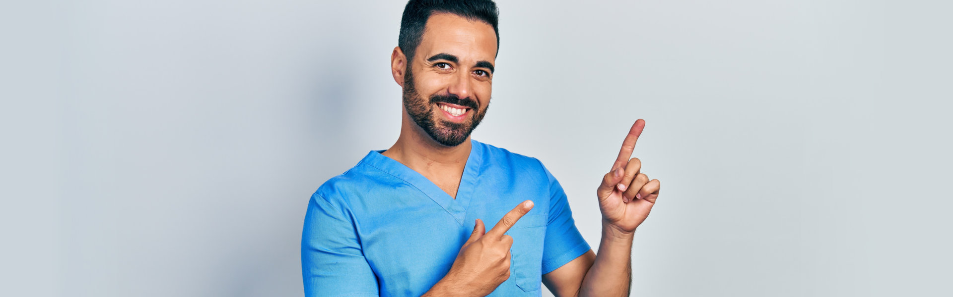 A male nurse smiling and pointing upwards