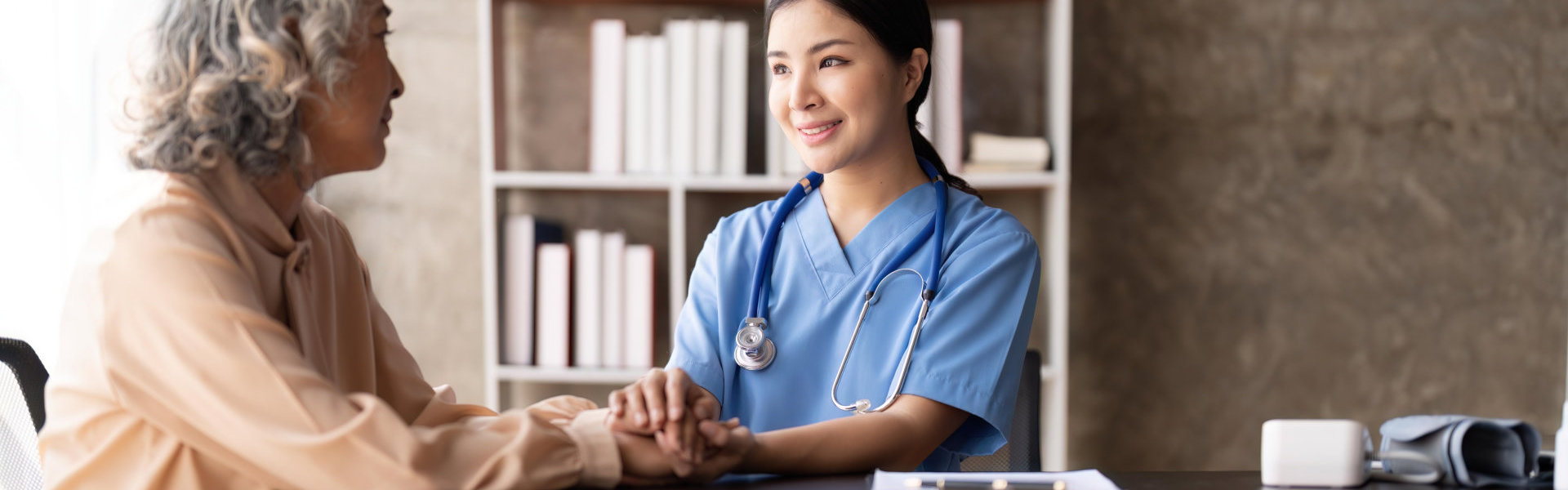 A nurse holding the hand of an elderly woman