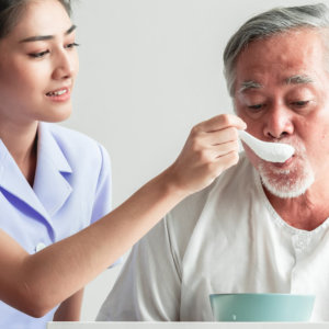 A woman feeding an elderly man